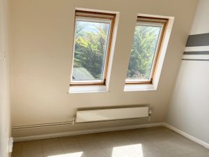 large slanting windows in a room with white walls