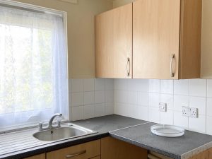 kitchen counter with wooden cabinet above and window