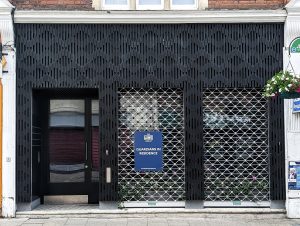 black building exterior with a blue sign that reads 'guardians in occupation'