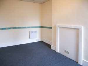 corner of a room with white walls and white fireplace, and blue strip of wallpaper with suns on it