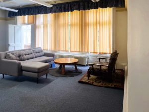 blue carpeted room with a round wooden table and yellow blinds