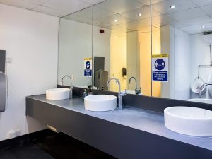 some kitchen sinks in a bathroom, below a large mirror