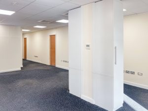 white walled corridor with blue carpet and brown wooden doors