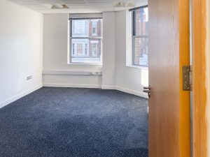 blue carpeted room with large windows and white walls