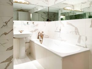 white bathroom with golden taps and mirrors on the wall