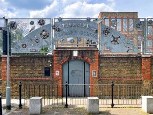 a red and brown brick building external with a silver metal sign reading Townsend primary school