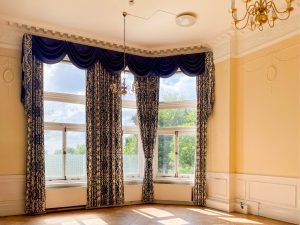 floor length dark blue curtains in a yellow-walled ballroom