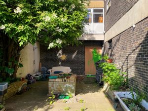 an overgrown garden outside a dark brick building