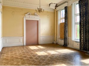 a yellow-walled ballroom with a chandelier and wooden floor
