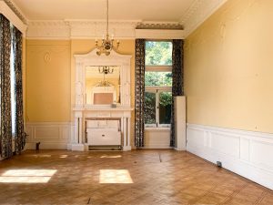a white fireplace in a yellow-walled ballroom with a wooden floor