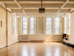 a large hall with a wooden floor and tall windows in the wall