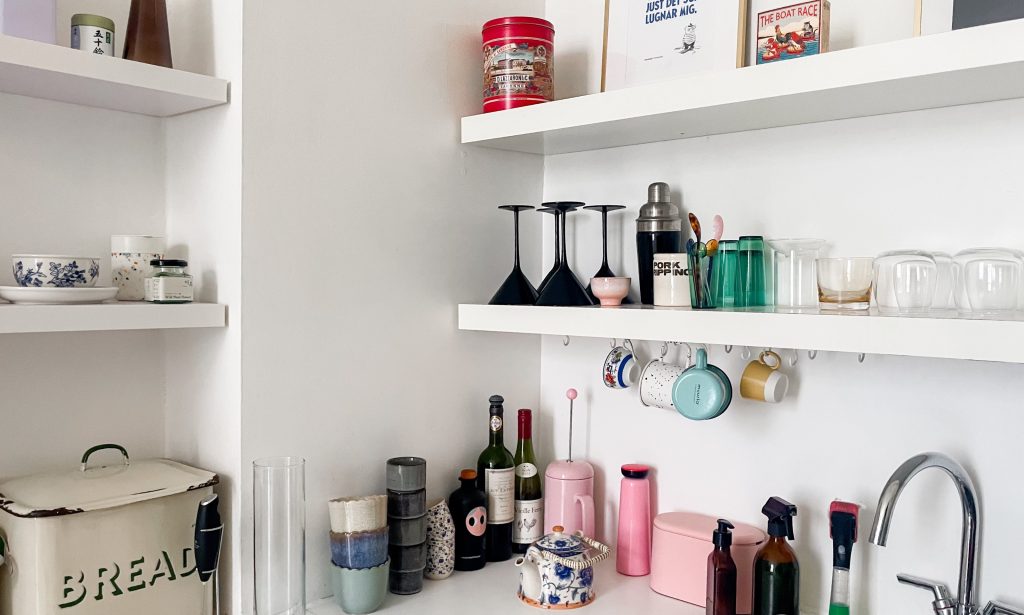a kitchen with white shelves built into the walls - the shelves contain black martini glasses