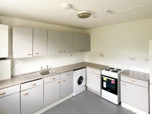 a kitchen with a washing machine, sink, cabinets and oven
