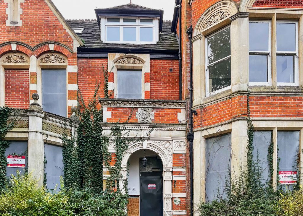 Red brick building exterior with green plants growing up the side
