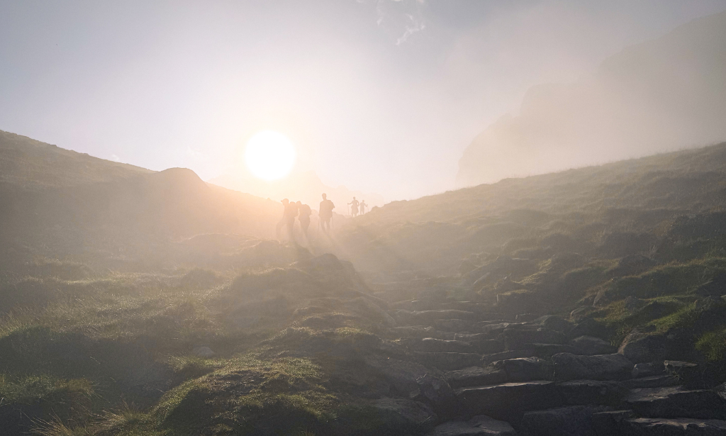 a foggy hill with silhouettes of hikers