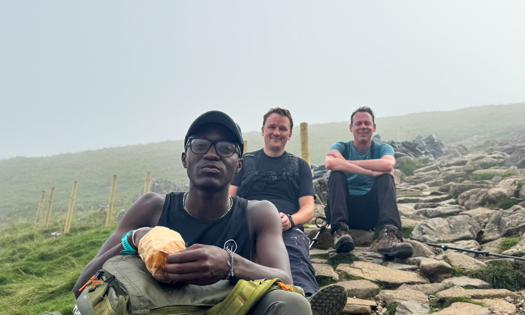 three men sitting on rocks in a field
