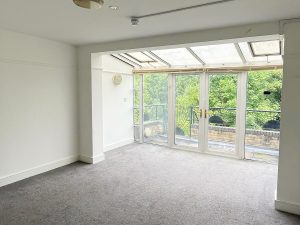 a room with french doors through which green trees can be seen