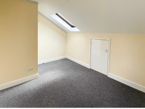 a room with a white slanting cieling and pale yellow walls