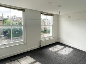 a room with grey carpted floor and two windows