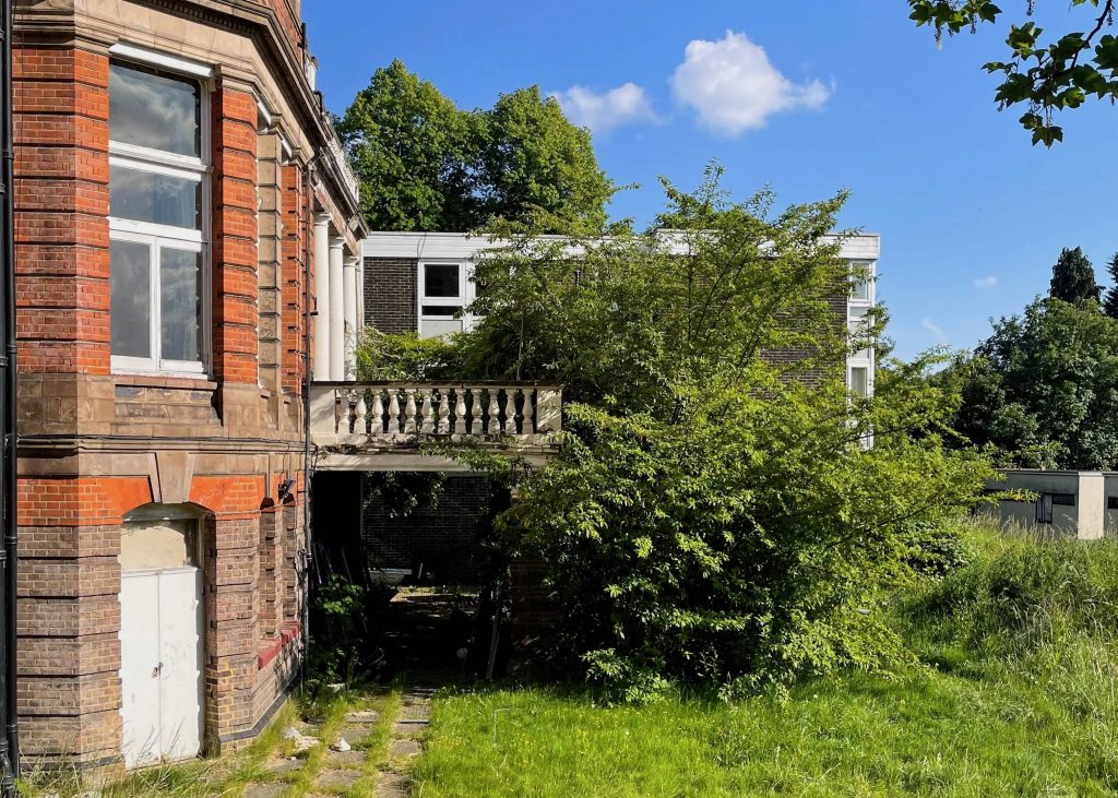 green overgrown plants in front of a red brick building exterior