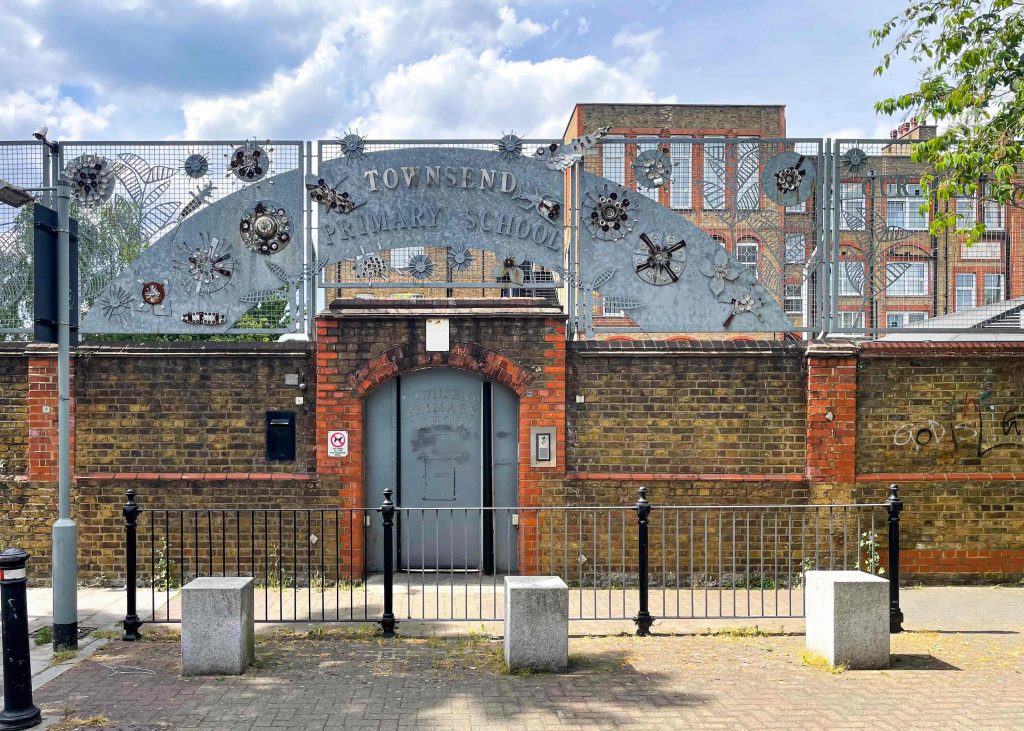 a red and brown brick building external with a silver metal sign reading Townsend primary school