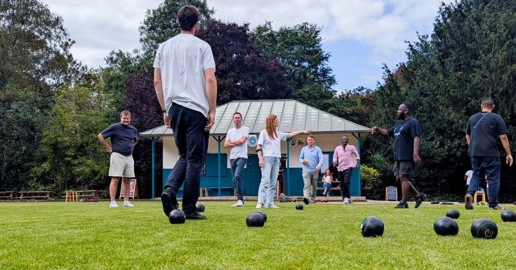 a group of people playing lawn bowls with black bowls on the grass